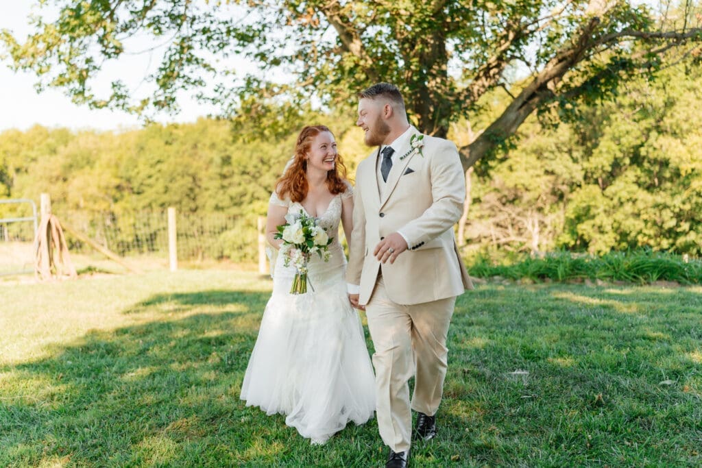 A bride and groom pose together outdoors in golden hour light during their wedding celebration in a scenic garden setting.
