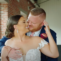 A bride and groom dance together in an intimate moment at an indoor wedding venue with exposed brick walls.