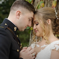 A close-up portrait of a bride and groom in military uniform sharing an intimate moment during their outdoor wedding ceremony at golden hour.
