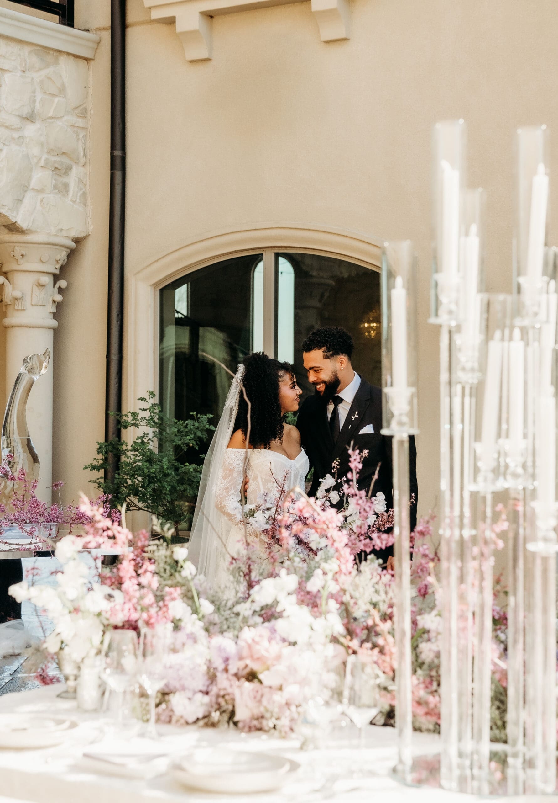 Couple standing in a doorway at their wedding reception with pink florals
