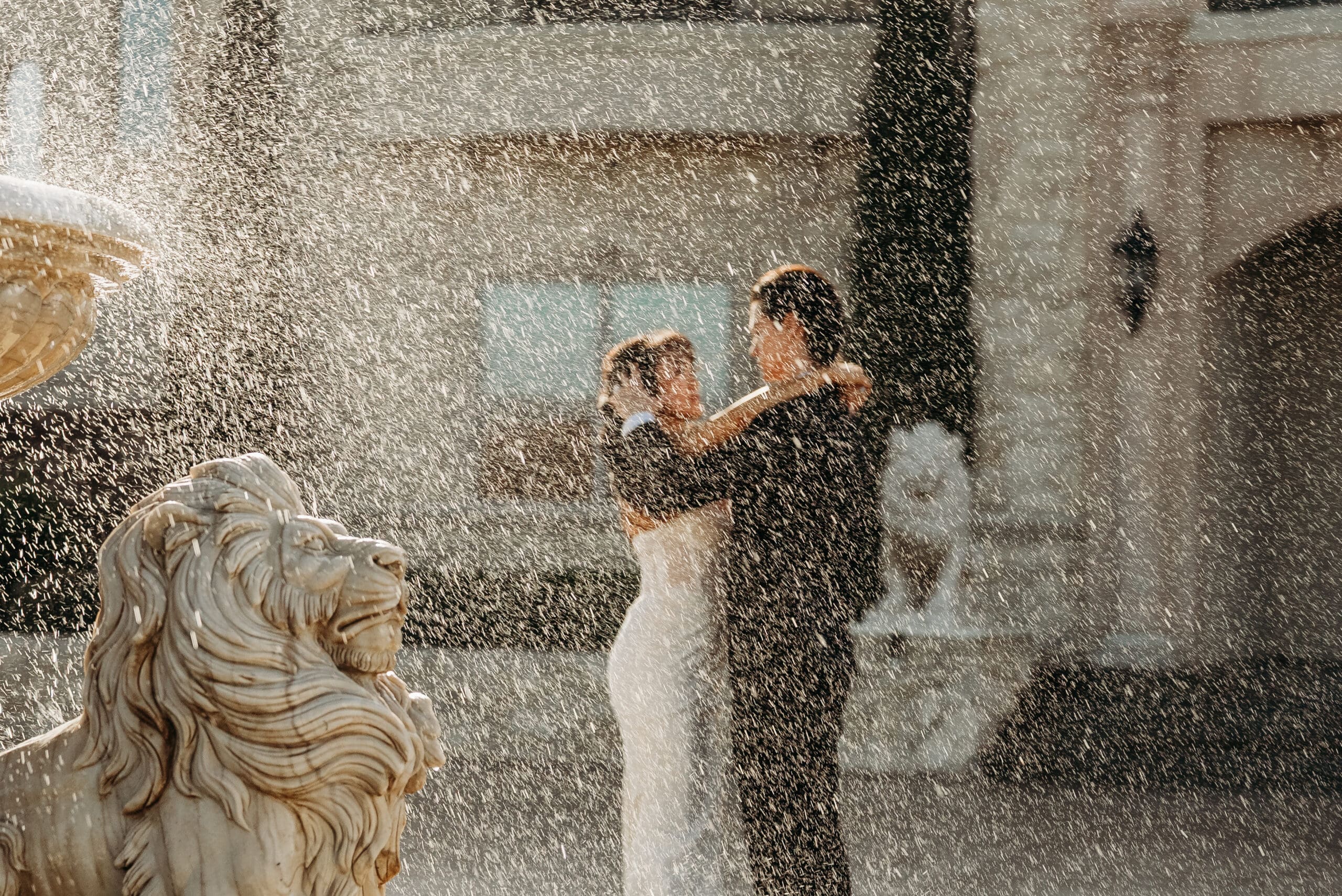 Bride holding a bouquet posing playfully at a fountain