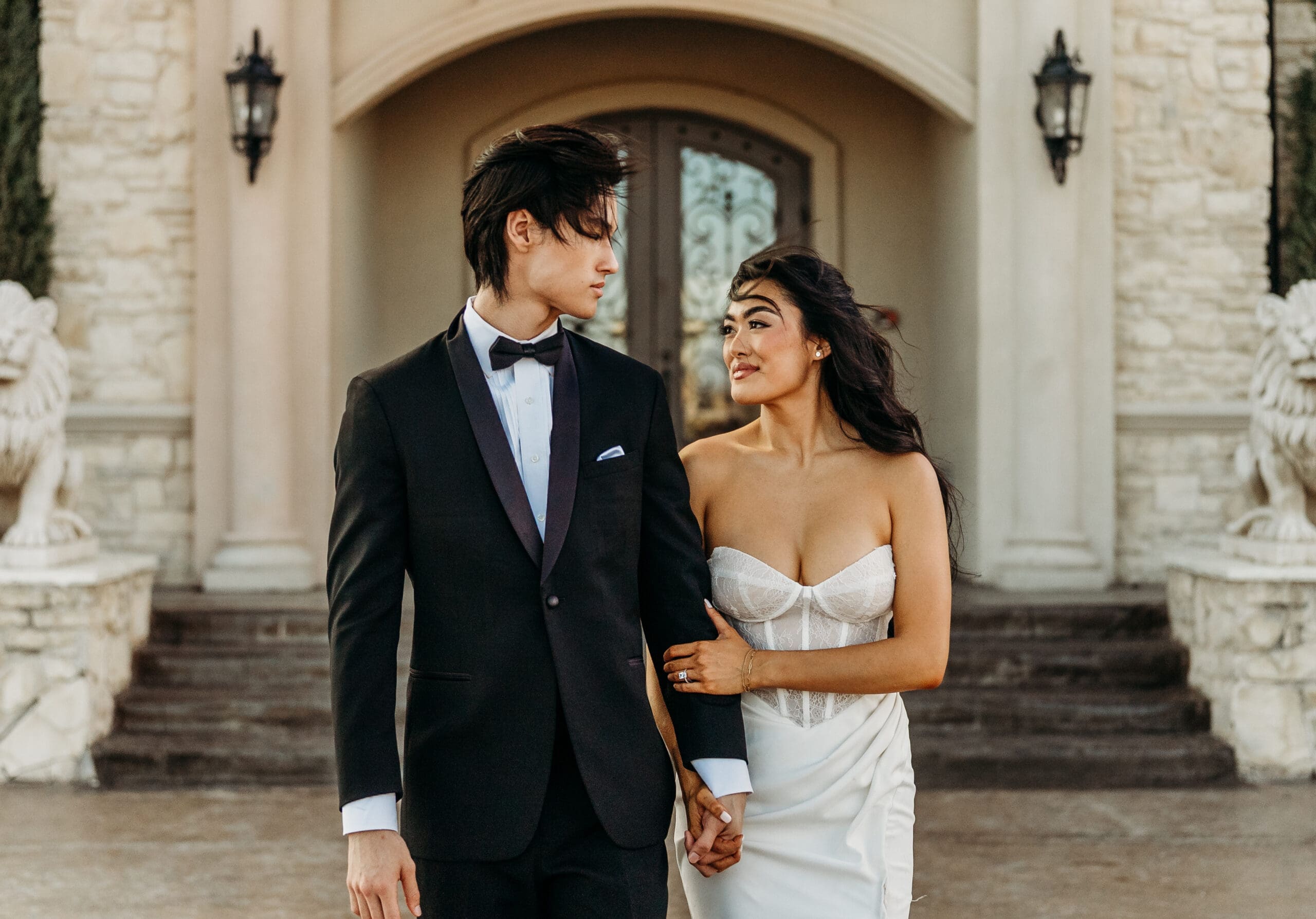 Bride and groom holding hands walking through an archway