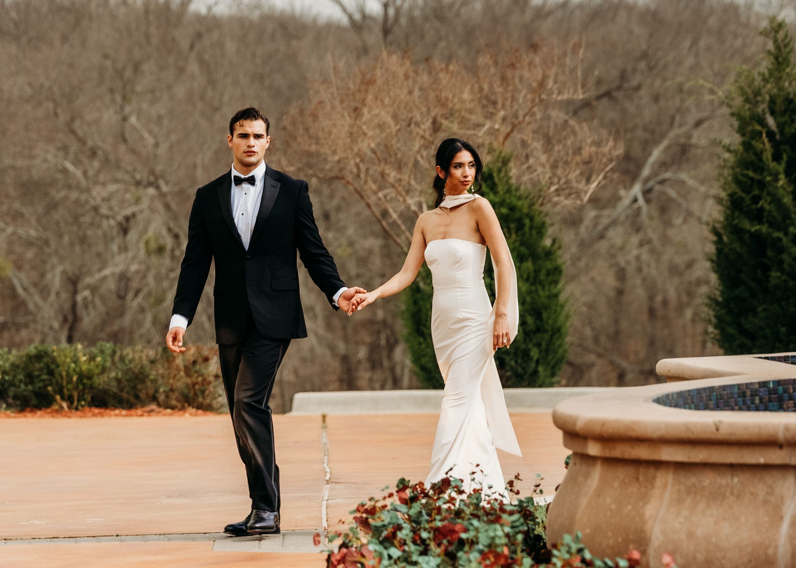 Bride and groom walk hand in hand through an elegant garden venue