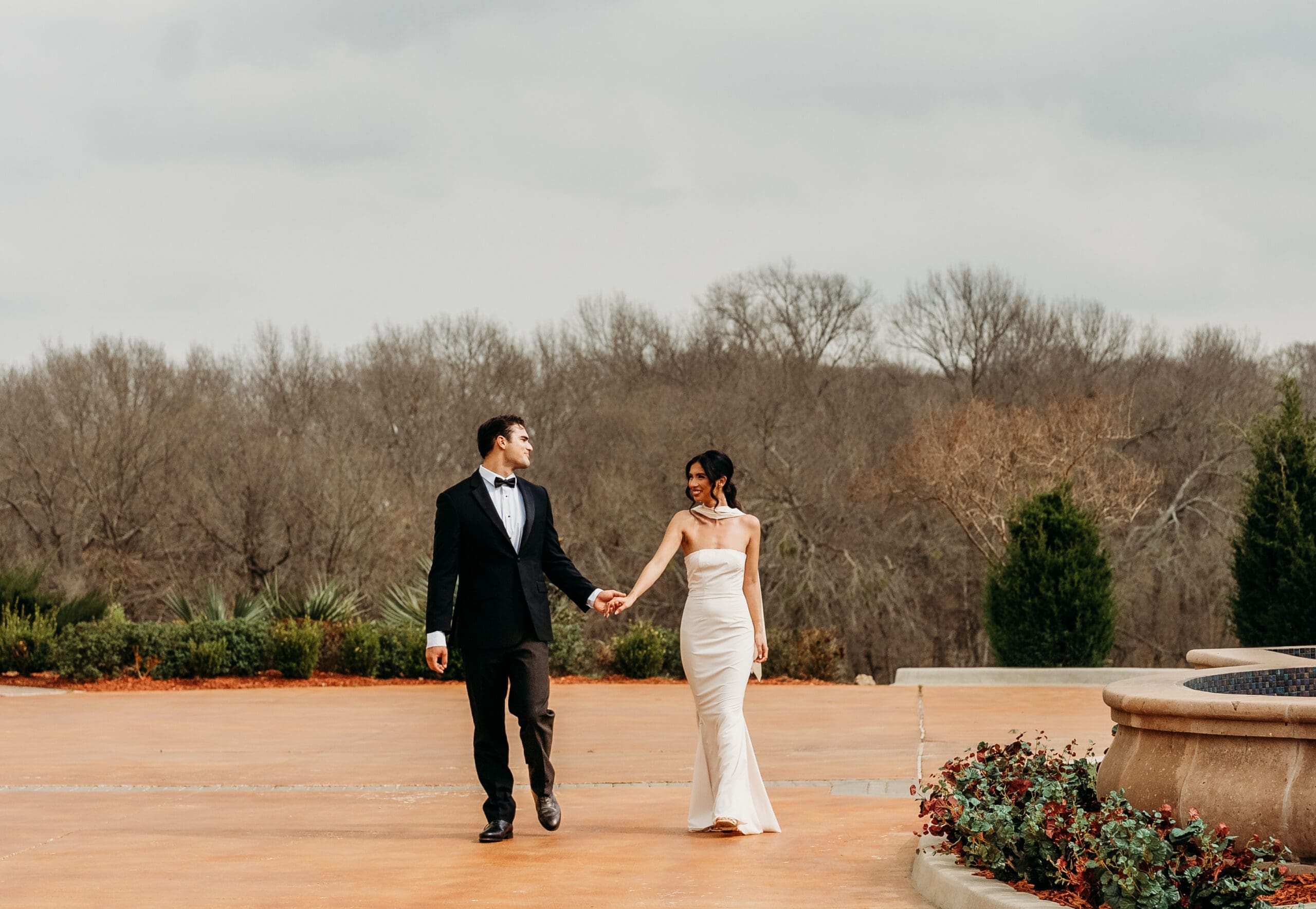 Bride and groom walk hand in hand across an outdoor venue