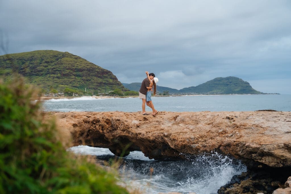 A runner jogs along a scenic beach with driftwood and ocean waves, with a distant island visible under a cloudy sky.
