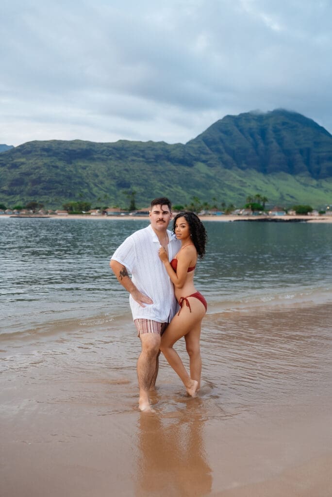 Couple in shallow tropical waters with mountain backdrop