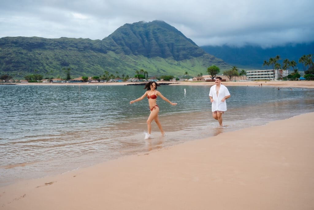Couple wading in turquoise tropical waters with dramatic mountains
