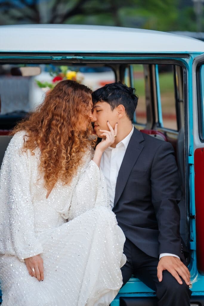 A bride and groom share an intimate moment inside a vintage teal and white van on their wedding day.